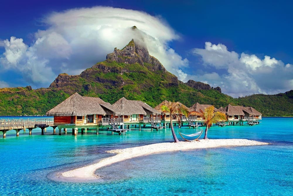 Imagem de um dos lugares paradisíacos no mundo chamado Polinésia Francesa, a imagem mostra um resort em uma ilha com água cristalina e um céu azul em um dia ensolarado